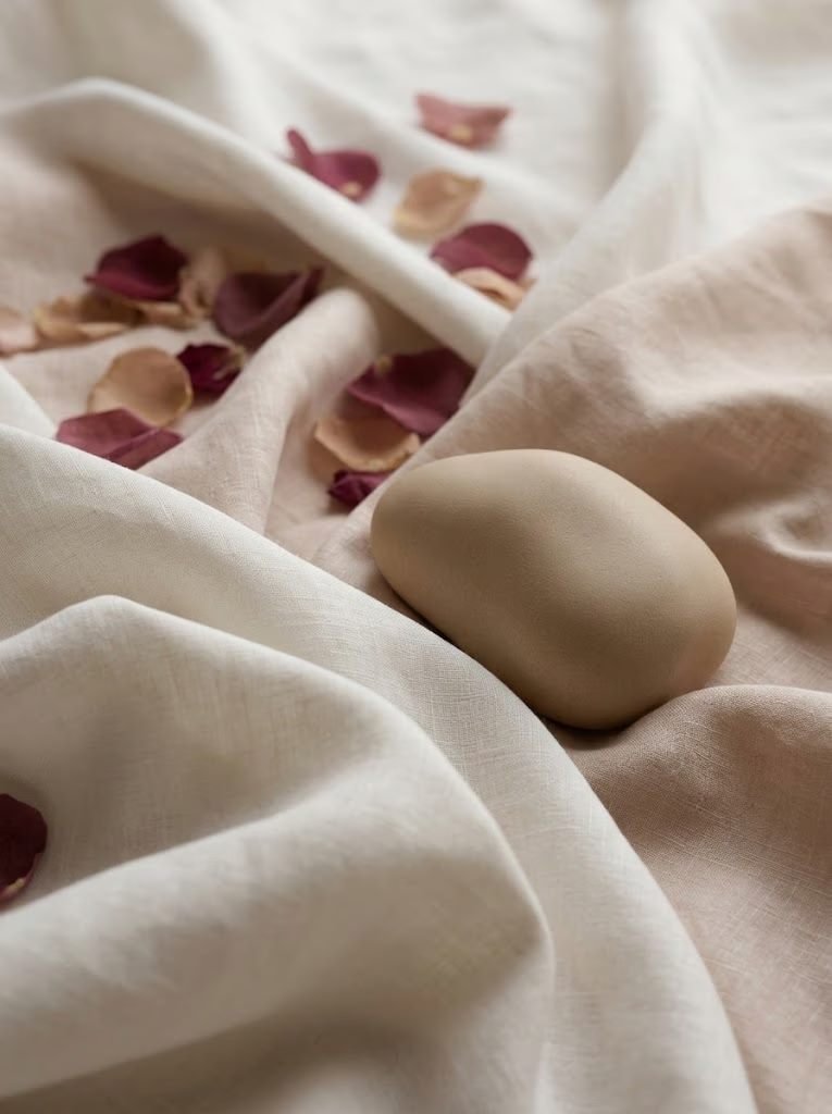 Tecido de linho com pétalas de rosa e uma pedra lisa